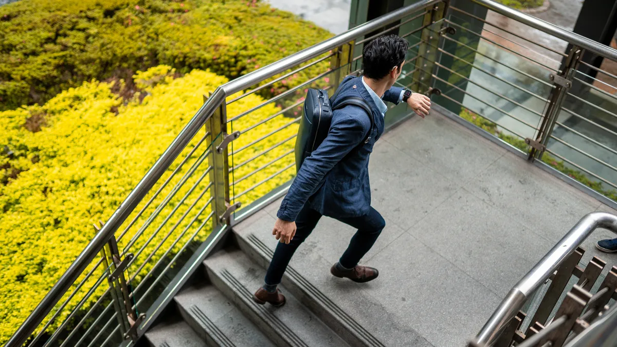 Business man moving upstairs and checking the time on his watch