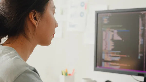 A person works on code on a computer monitor.