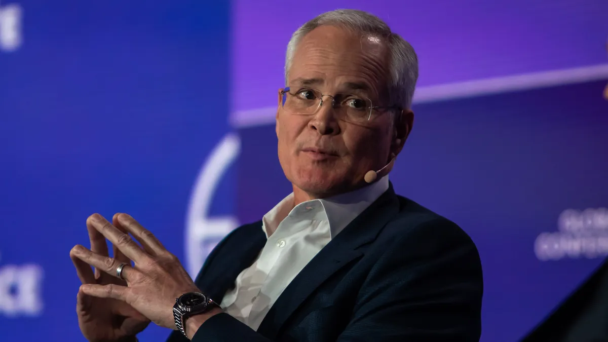 ExxonMobil CEO Darren Woods sits with hands folded