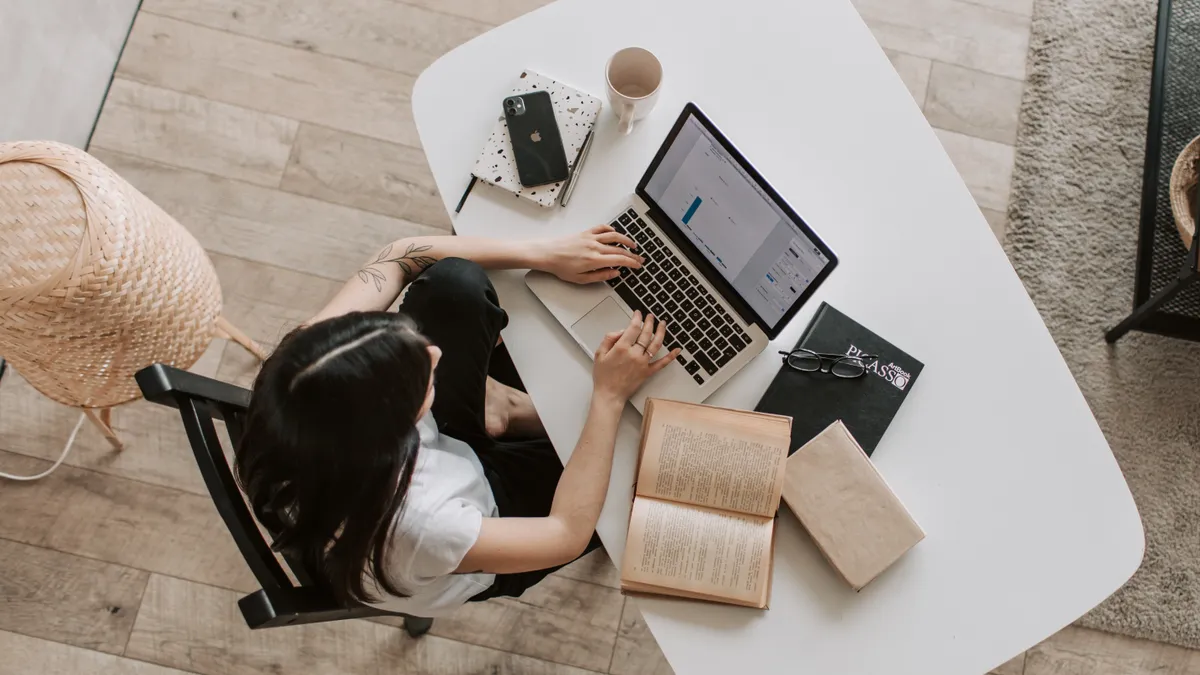 An aerial view of a dark-haired woman typing on a laptop at home