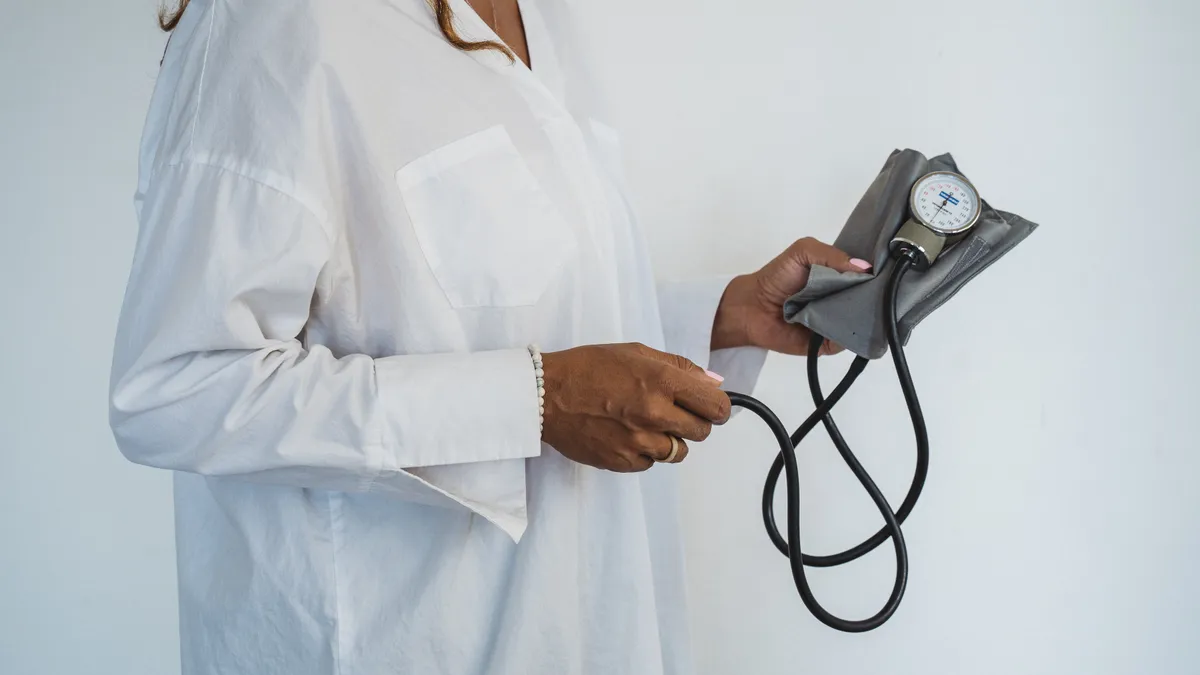 A Black person holds a blood pressure pump