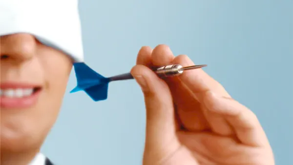 Blindfolded person throwing a metal dart