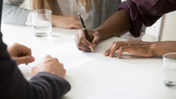 A close-up of a two people signing legal documents.