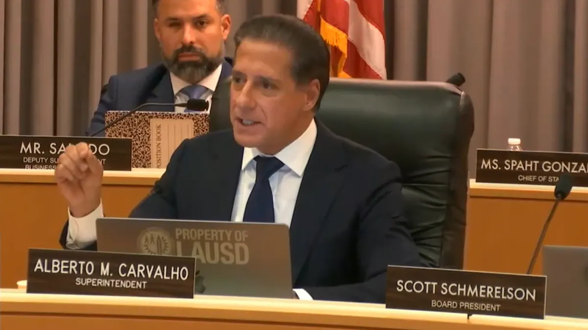 Alberto Carvalho speaks while sitting at a table during a school board meeting.