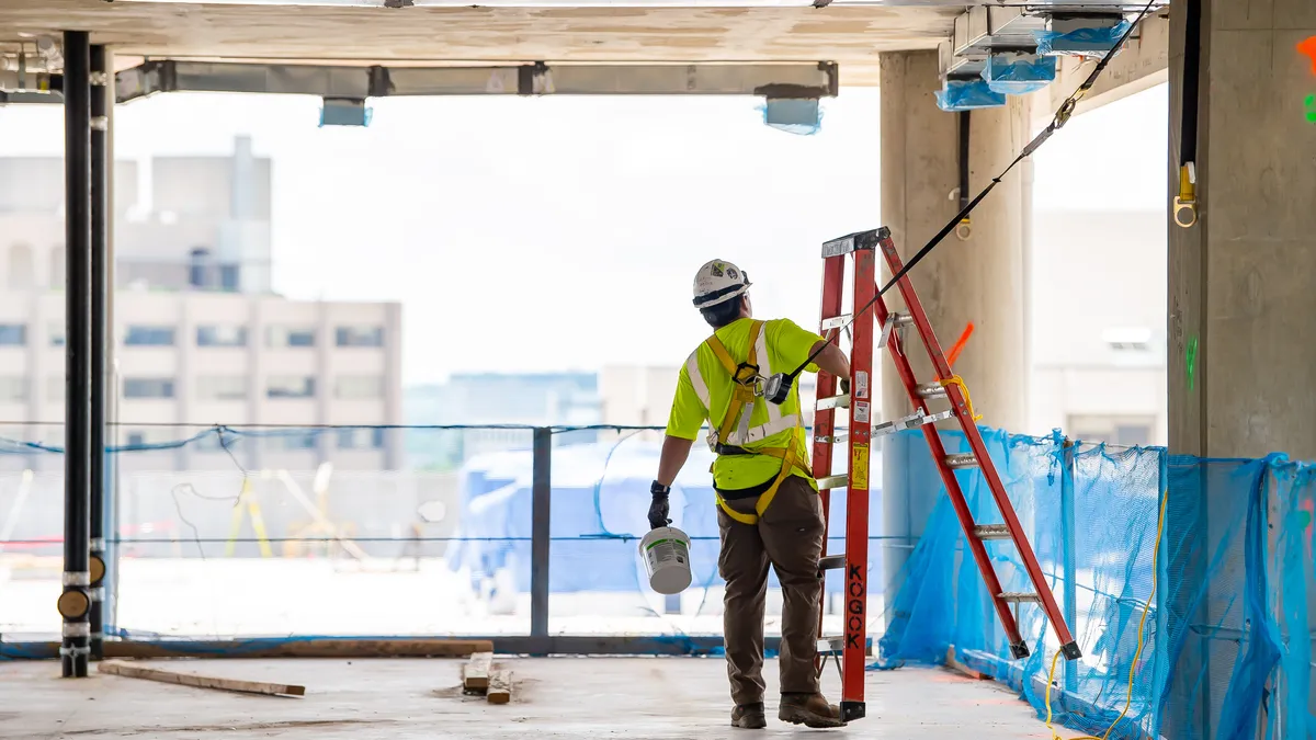 A construction worker moves a ladder.