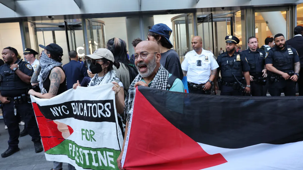 Protestors hold a banner and wear kaffiyahs