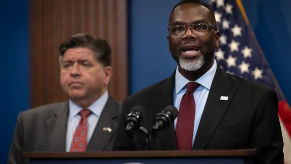 Person speaking at podium with another person behind.
