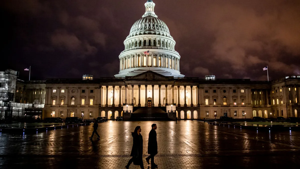 People walk along the east front plaza of the US Capitol as night falls on December 17, 2019 in Washington, DC.