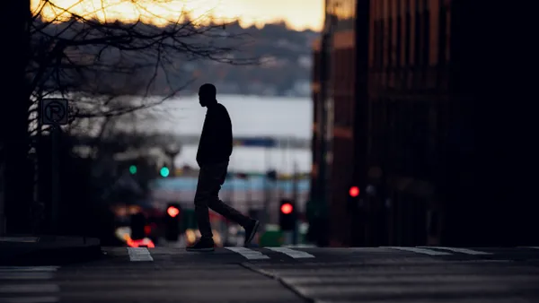 Silhouette of a man crossing a dark street.