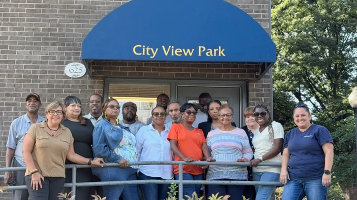 People standing in front of a brick apartment below a