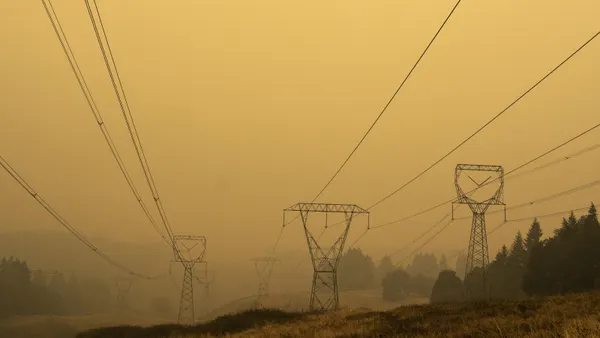Transmission lines run into the distance against a hazy sky.