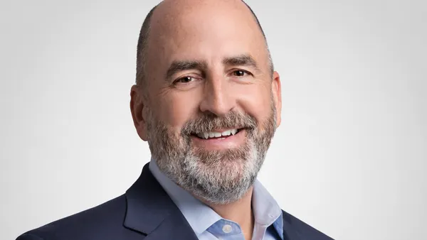 Michael Iskra, wearing a navy blue jacket and light blue shirt, smiles in a head shot.