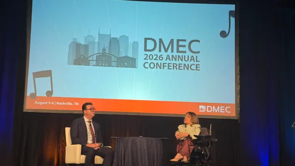 Two people sit on a stage during a conference