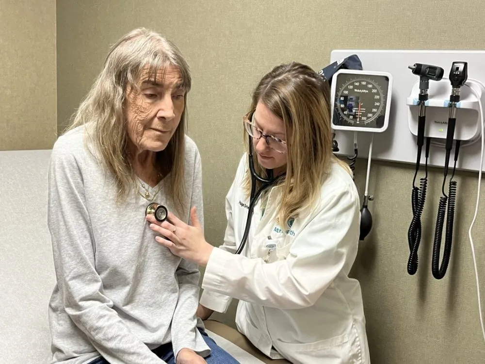 A doctor holds a stethoscope to an elderly patient's chest.