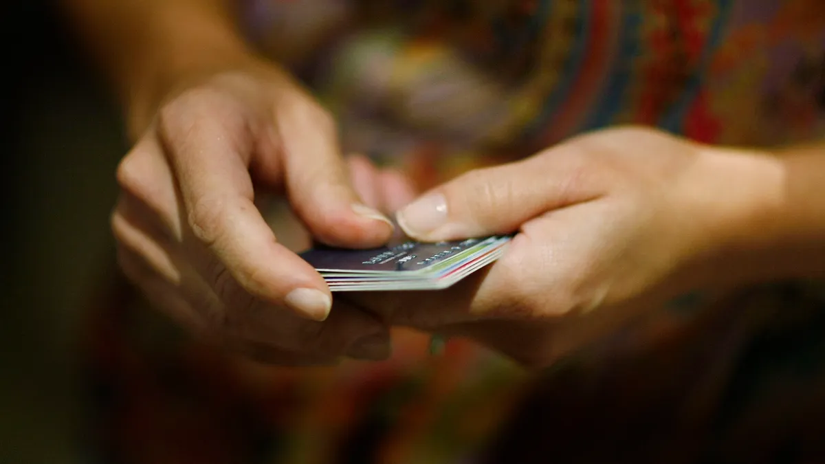 Closeup of a person's hands holding several credit cards.