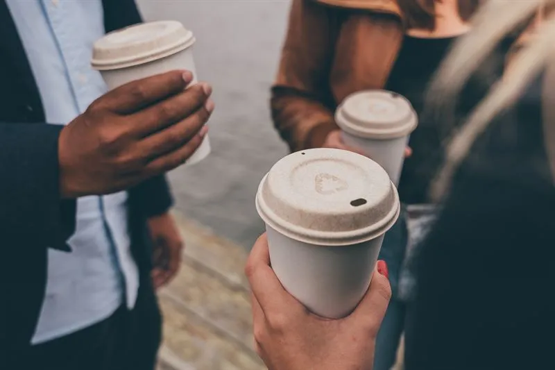 People holding coffee cups with natural-colored, fiber-based lids.