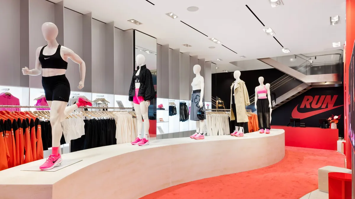 A line of mannequins in running apparel above a red carpet and a Nike logo.