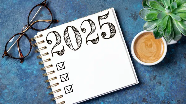 2025 resolutions list with notebook, coffee cup on table.