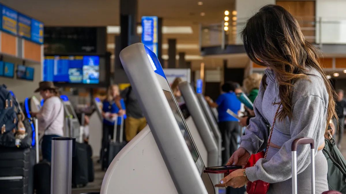 A passenger checks-in for their flight at an airport kiosk.