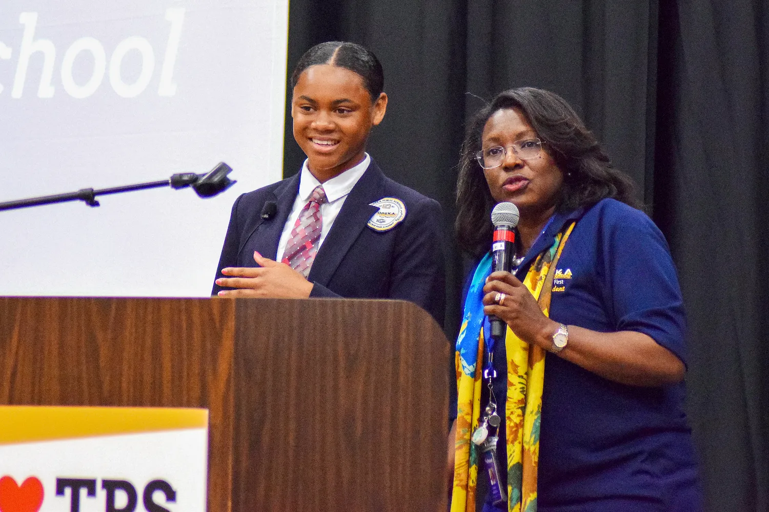 Topeka Public Schools student Simone Holloway stands onstage with Superintendent Tiffany Anderson at a school district event.