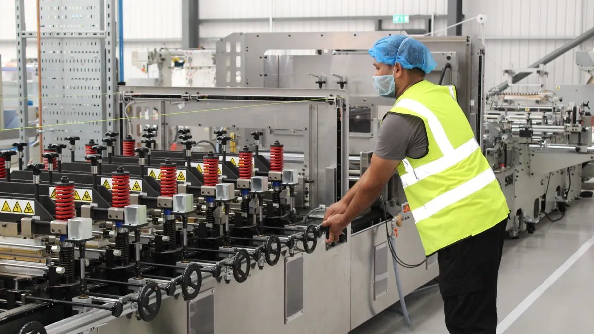 An operator adjusts a pouch-making machine at an ePac Flexible Packaging facility.