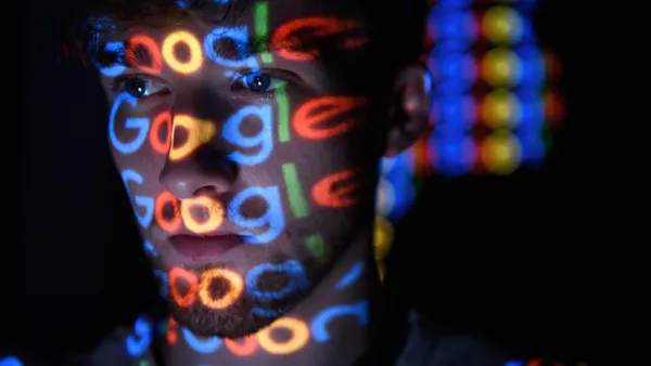 Google's logo is reflected from a screen onto a man
