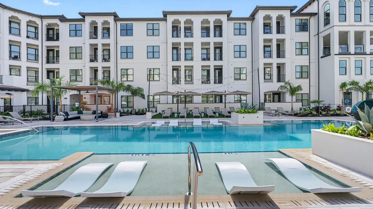 White mid-rise apartment with pool in the foreground