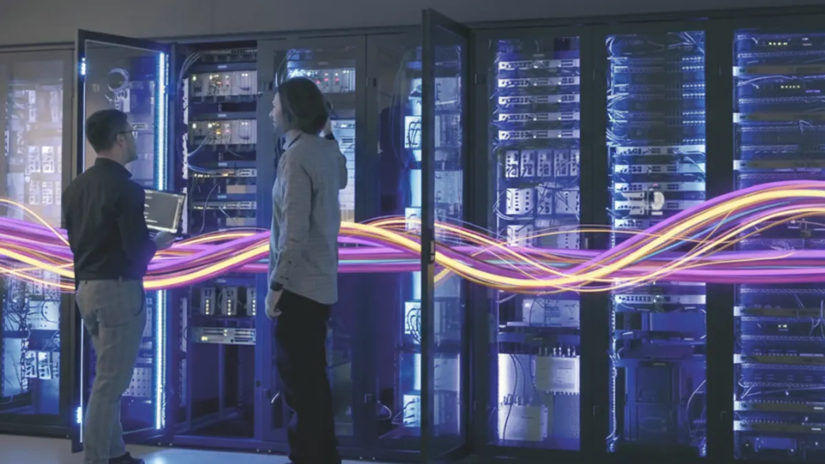 2 people standing in front of a lot of computer servers.
