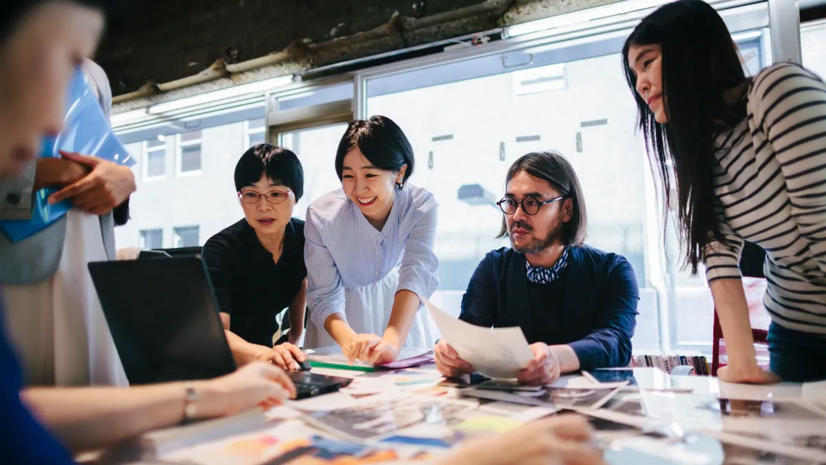 Professionals looking at a laptop collaborating on a project