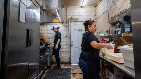 Two employees work in a professional kitchen.