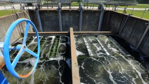A rusty wheel with blue chipping paint above a concrete basin with flowing water.