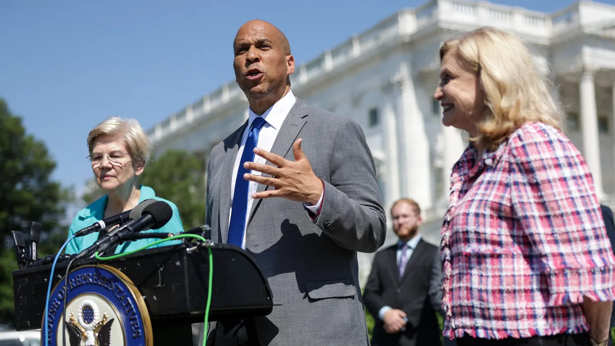 Lawmakers stand behind a lectern in front of the U.S. Capital.