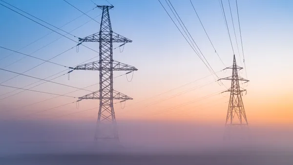 Transmission towers in fog at dawn.