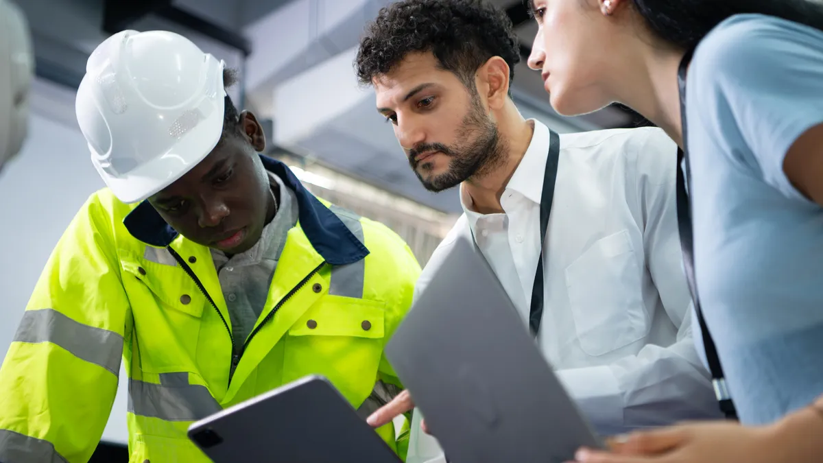 An engineer and building managers look at data on a tablet.