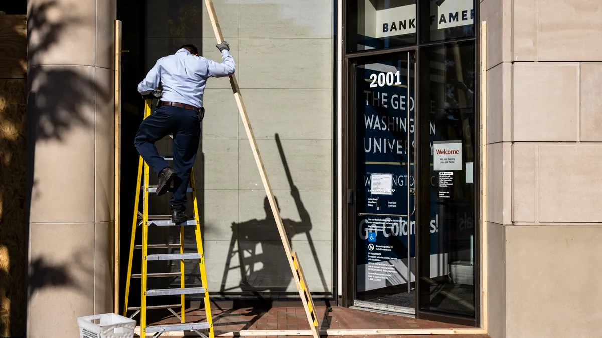 A maintenance worker climbs a ladder outside a building.