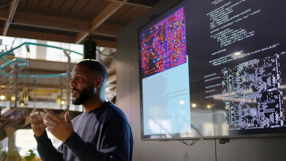 Photograph of a man conducting a seminar on Python computer coding in an open plan work arena.