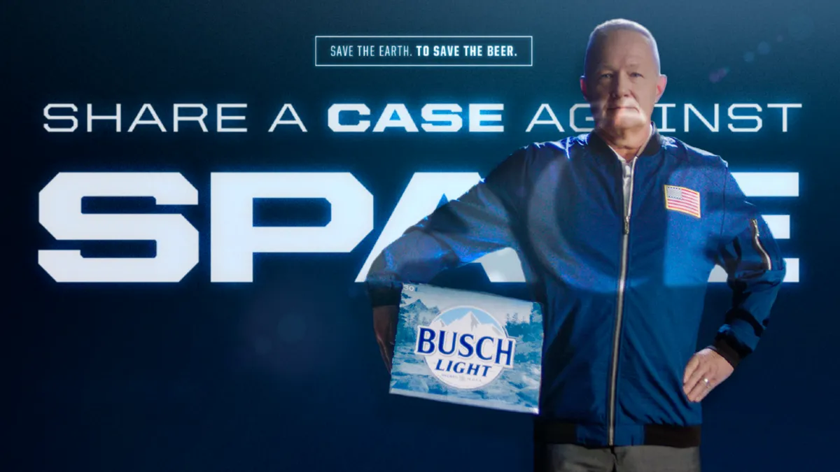 Astronaut Doug Hurley holds a case of beer under his arm in front of an image of Earth.