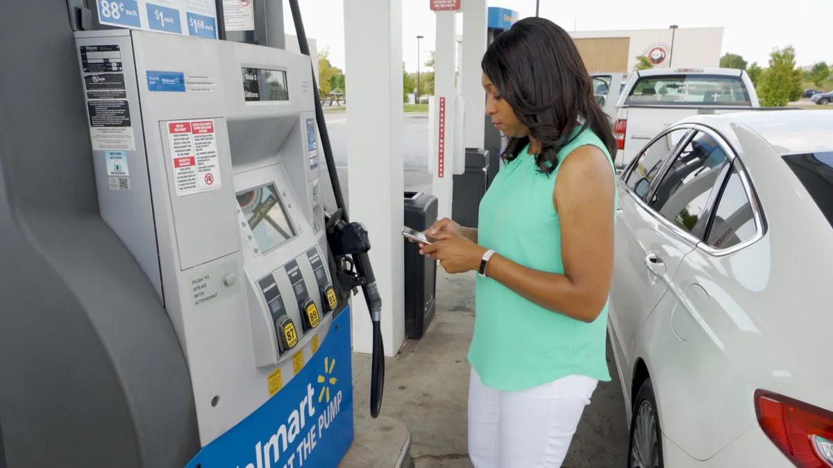 A photo of a woman using Walmart + rewards at the gas pump.