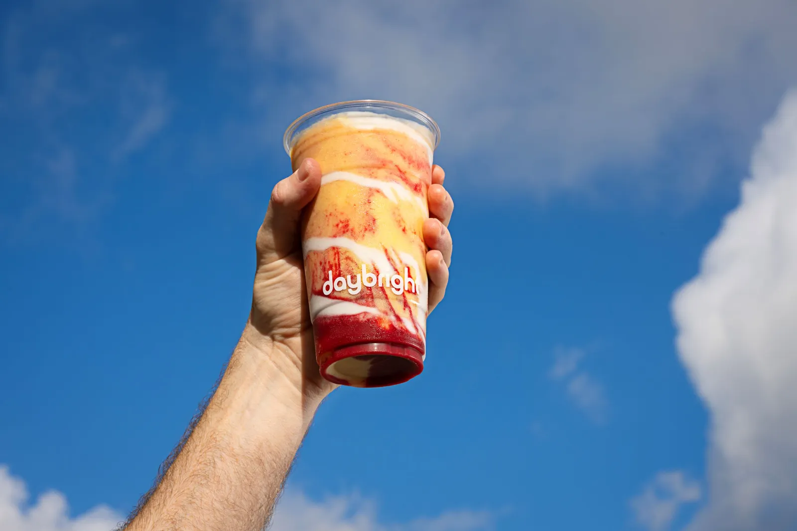 An image of a hand holding up a mulit-colored drink