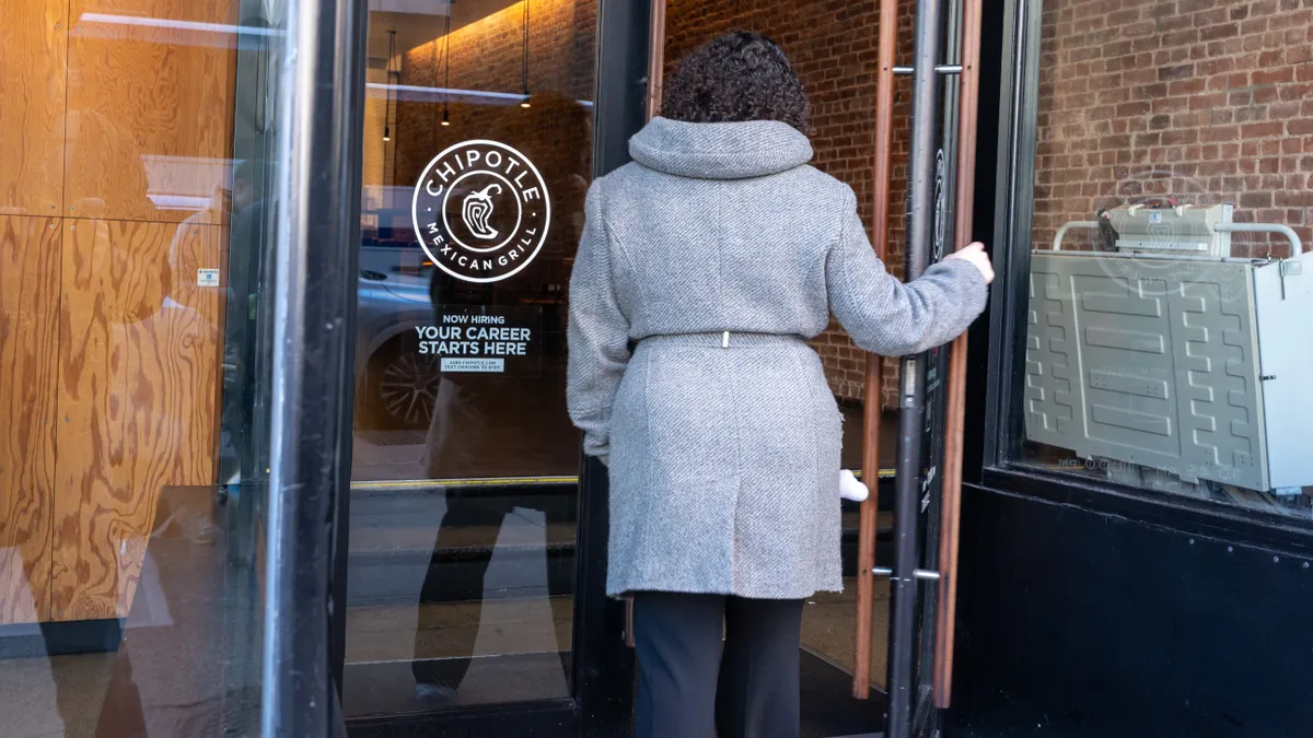 Woman opening the door to a Chipotle location in Manhattan in Feb 2014