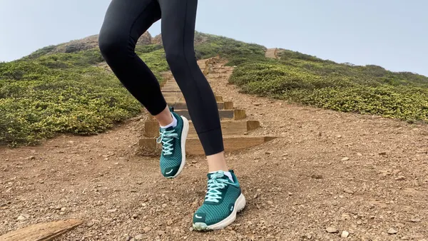 A person running down a hill wearing teal sneakers