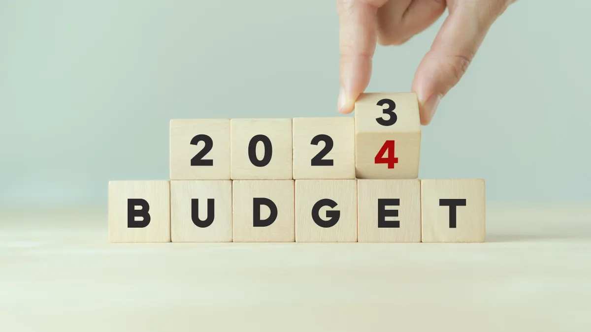 Hand flips wooden cube and changes the inscription from "BUDGET 2023" to "BUDGET 2024"