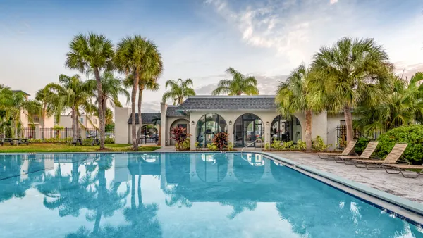 A pool surrounded by chairs at an apartment community.