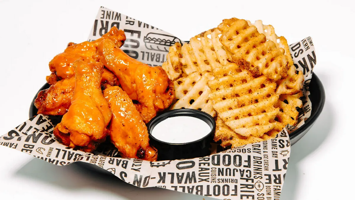 Bone-in wings from Walk-On's with waffle fries in a paper plate.