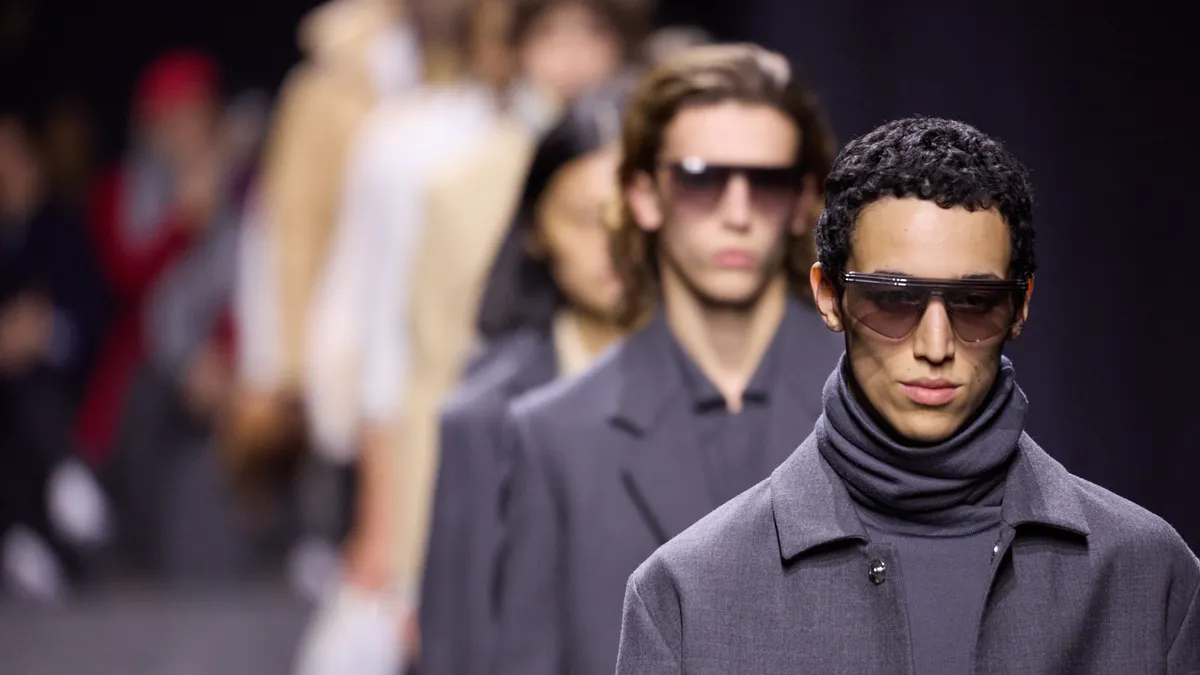 Closeup of model faces in sunglasses and suiting as they walk the runway for the Zegna menswear fashion show in Milan.