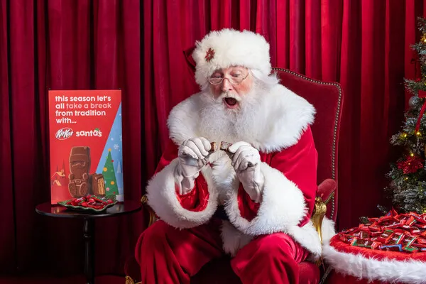 Santa Claus opening a Kit-Kat Bar in a Santa Claus shape.