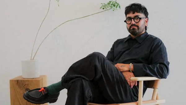 Daniel De Jesus Krueger sits in a chair for a professional headshot.