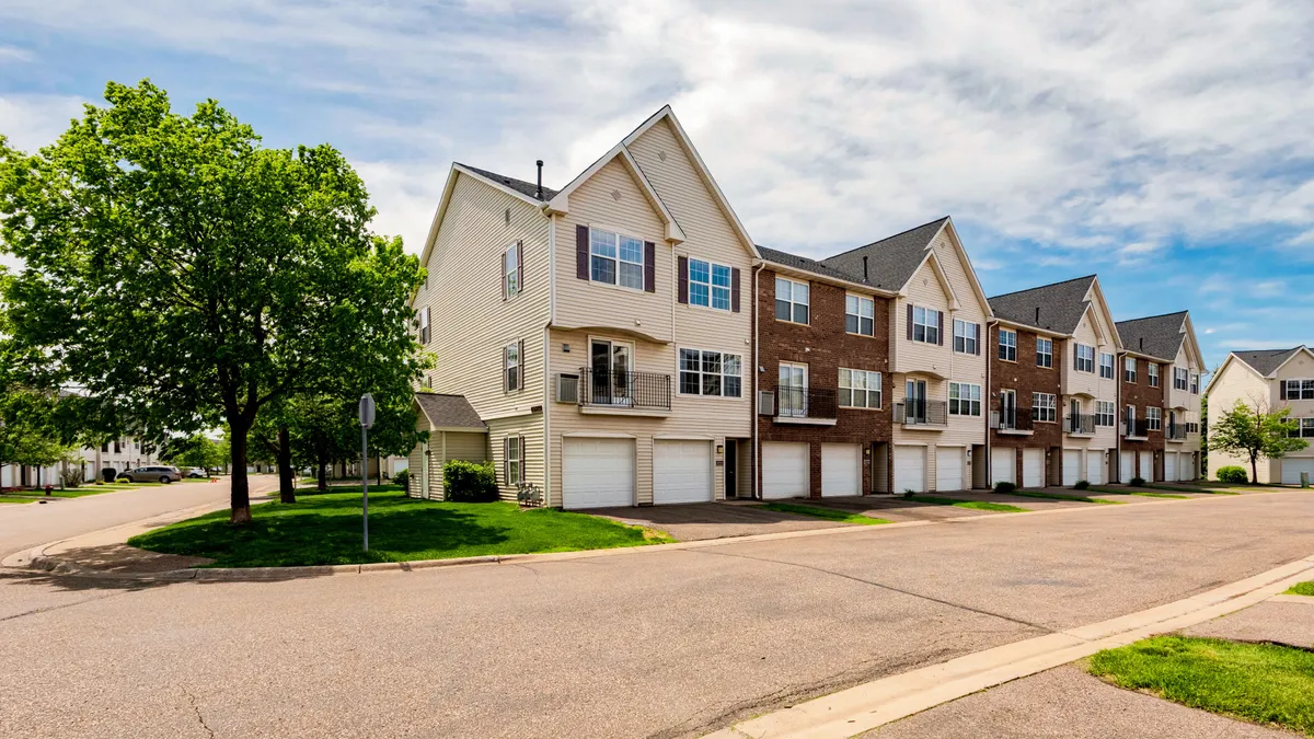 Corner view of tan and brick townhome community.