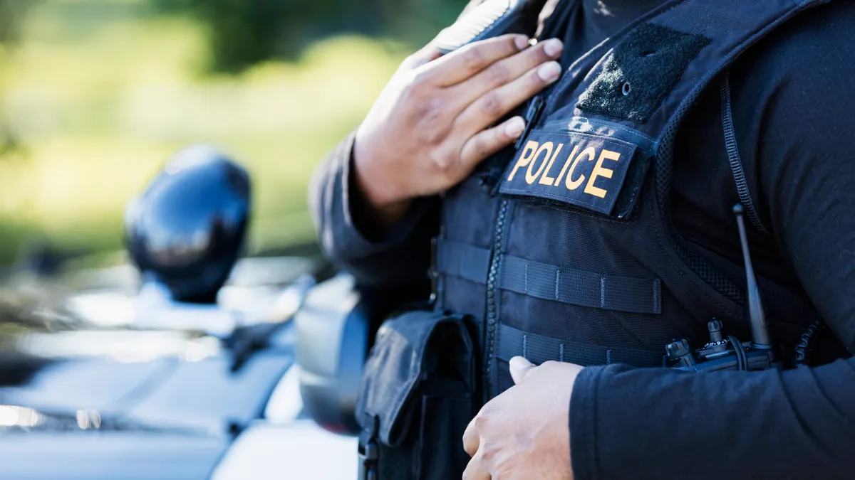 Cropped view of a person wearing a blue uniform that says "POLICE"