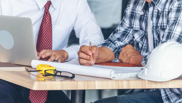 Contractor construction engineer meeting together on architect table at construction site.